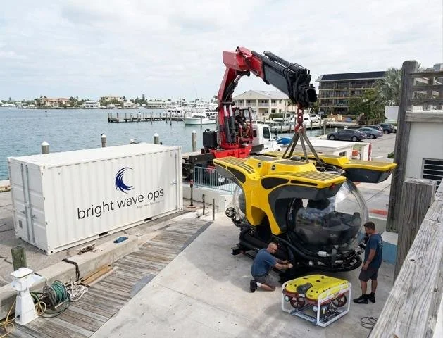 Bright Wave team preparing a yellow submersible beside its branded support container
